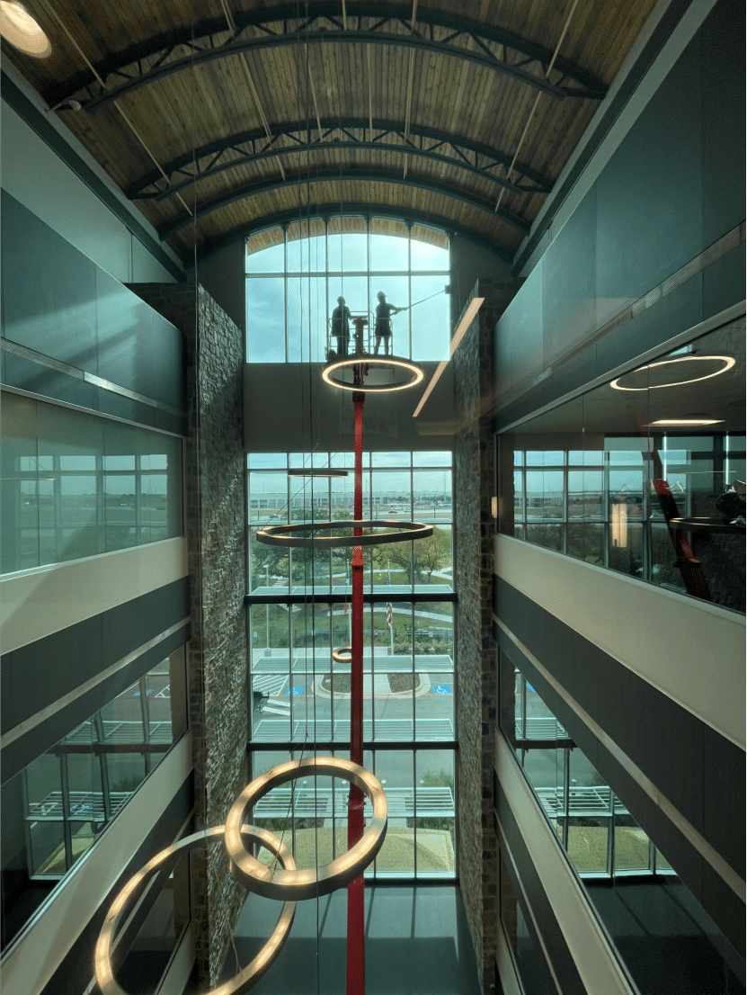 Two professional window cleaners using a hydraulic lift to clean the windows of a commercial building.