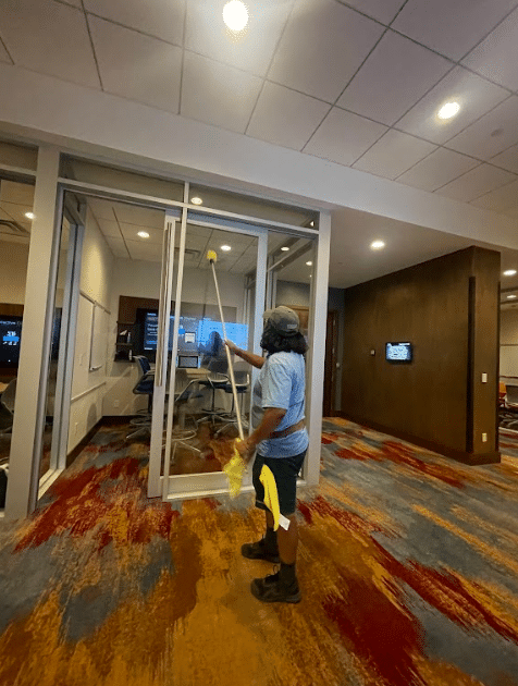 Professional window cleaner cleaning a commercial building's glass interior
