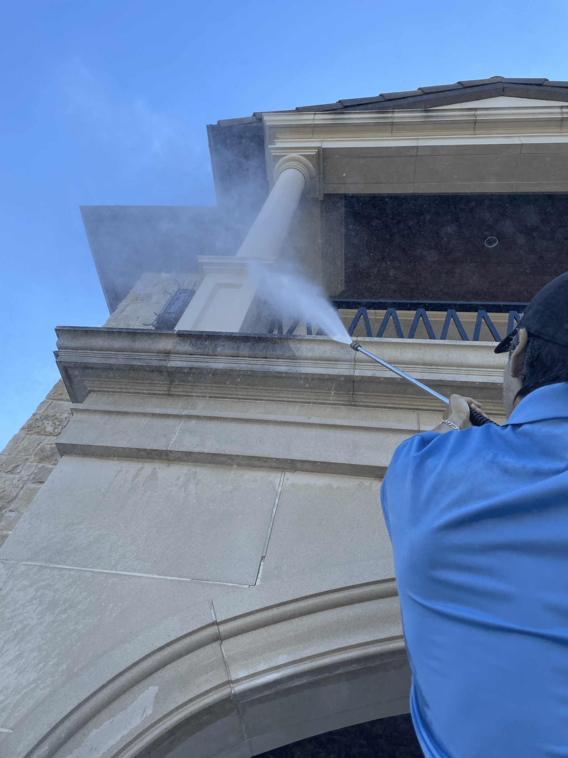 A professional technician power washing the exterior walls of a commercial building in the Dallas-Fort Worth area.