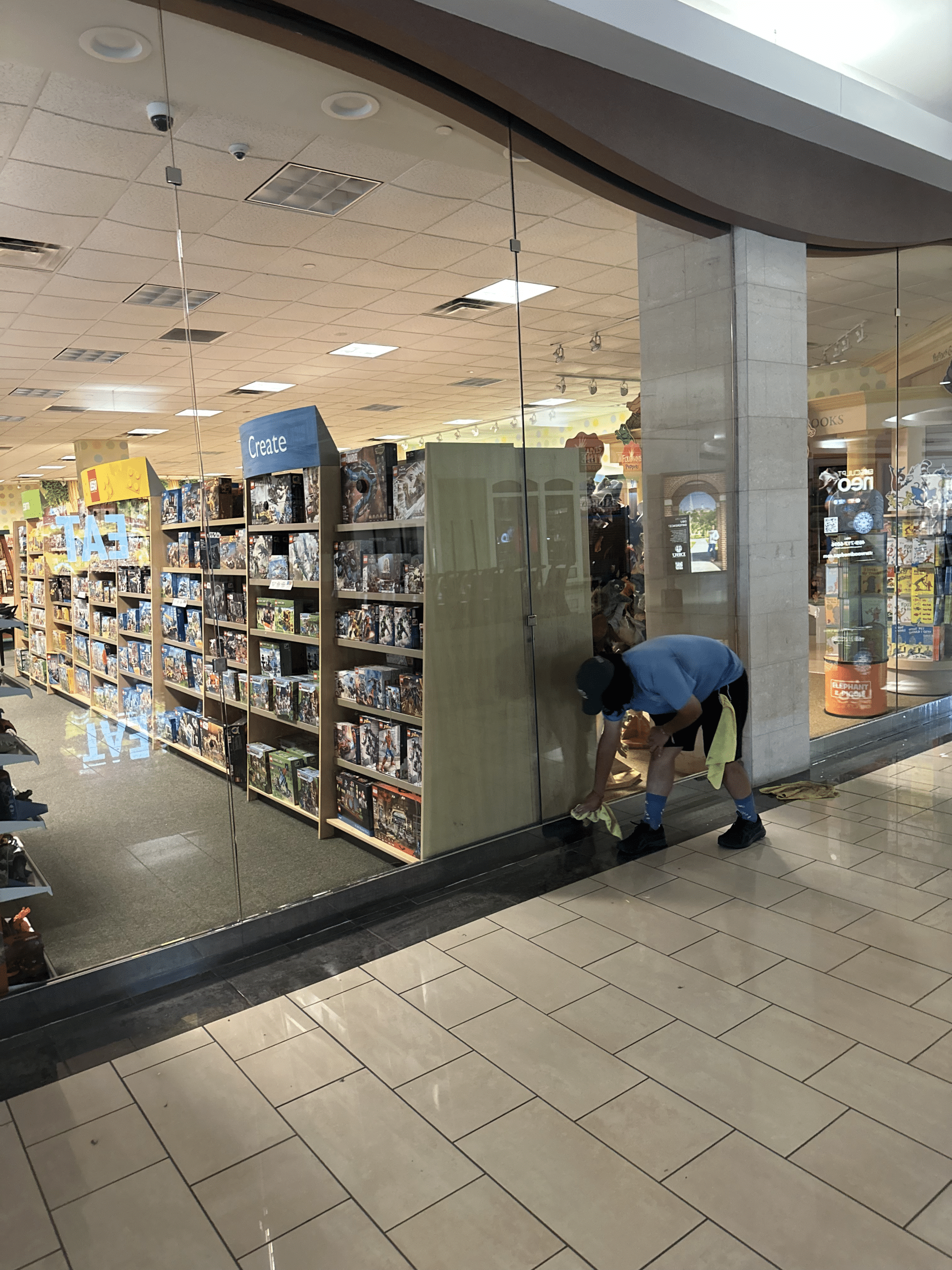 A professional cleaner washing the glass windows of a storefront