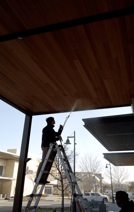 An image of a man pressure washing a commercial building’s ceiling