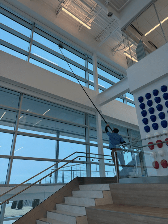 An image of a man cleaning a high window