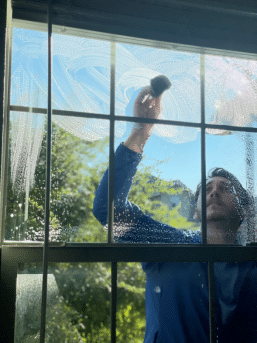 A worker from Bellah Cleaning Company cleaning a window fo a residential property