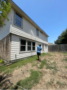 A worker from Bellah Cleaning Company power washing a residential property