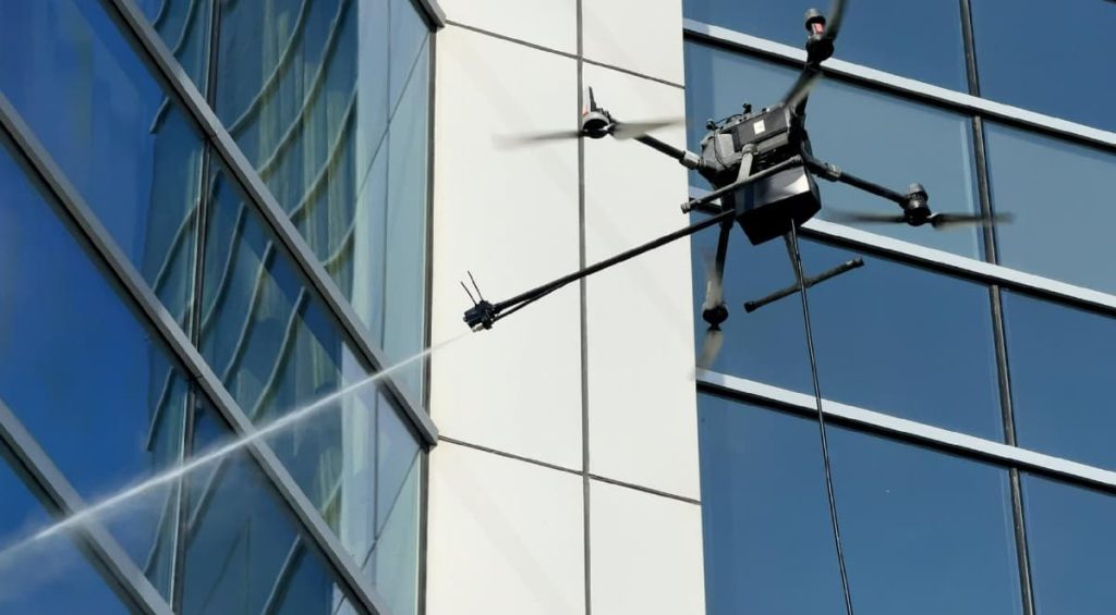 Commercial drone window cleaning service washing the exterior glass of a multi-story building